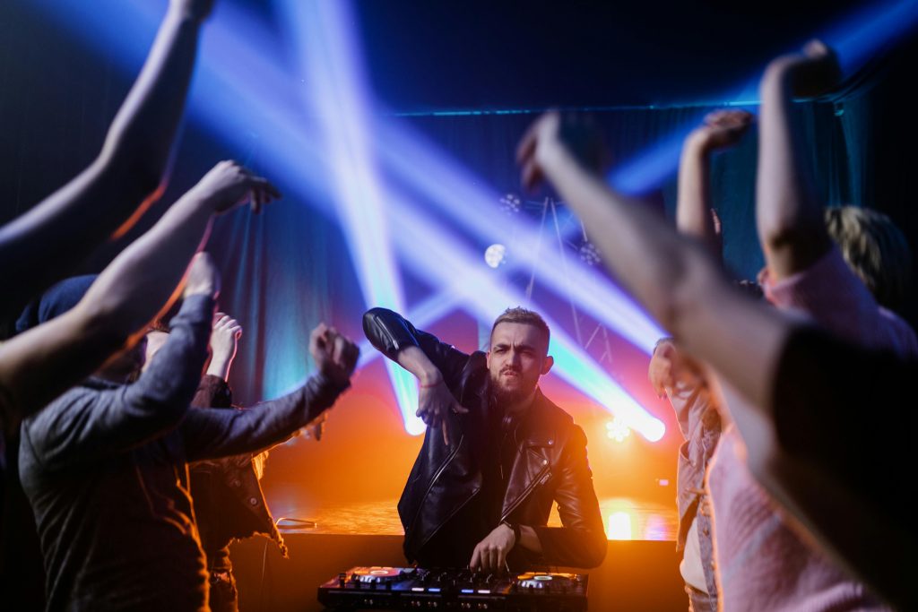 DJ entertains energetic crowd with dynamic music and vibrant lights.